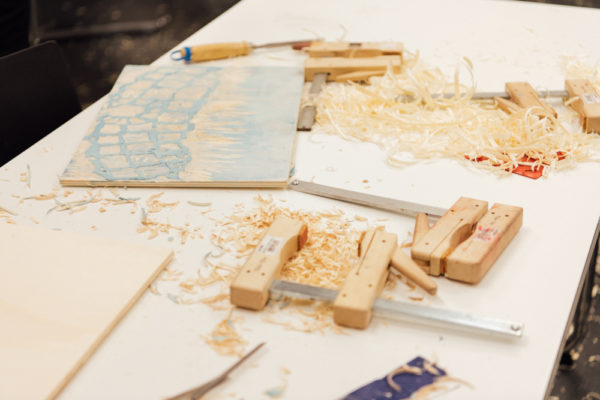 Werkzeuge, Späne und Holzschnittplatten auf einem Tisch.